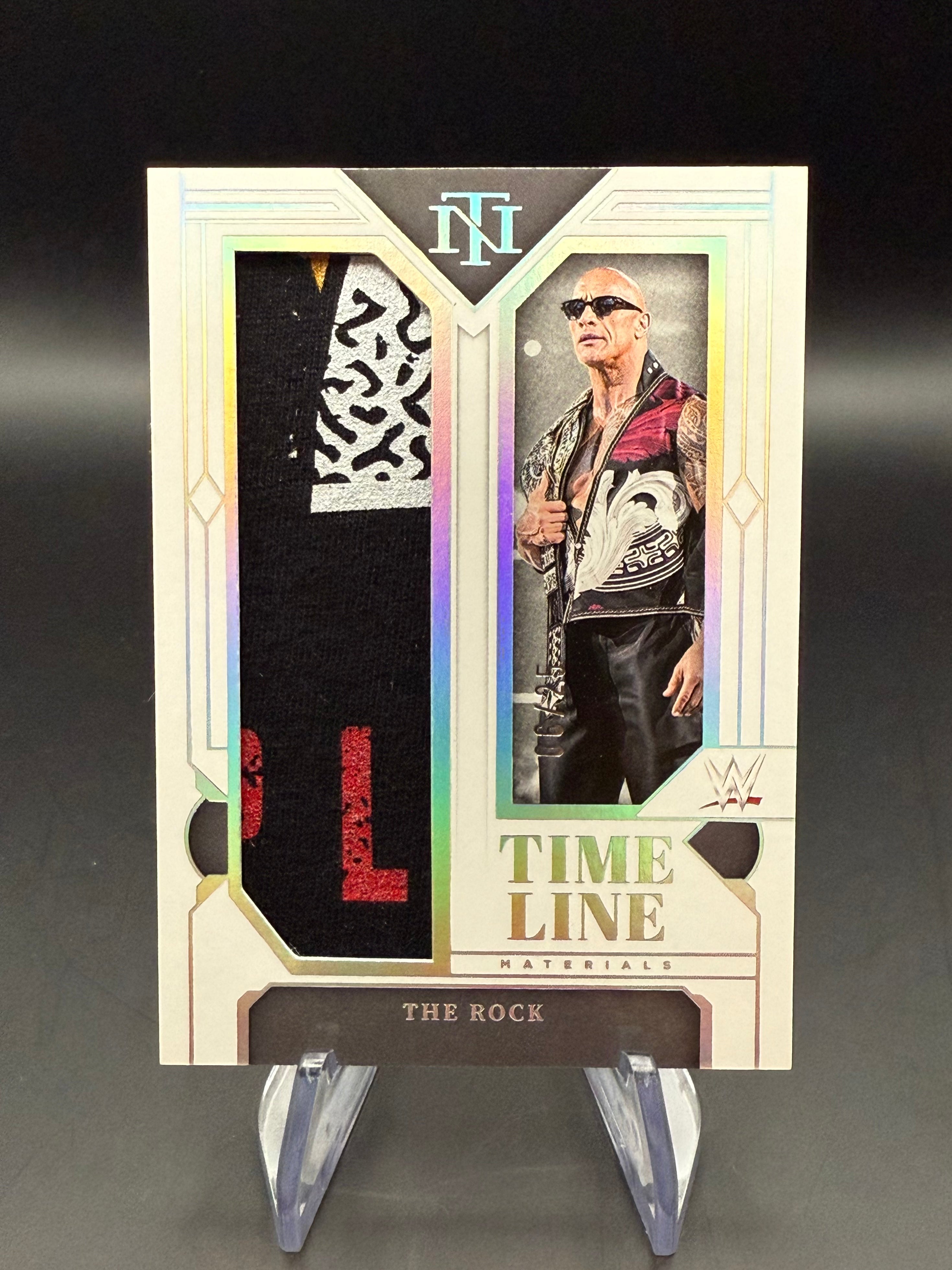 The Rock 2024 WWE Panini National Treasures Timeline Materials Holo Silver Relic /25